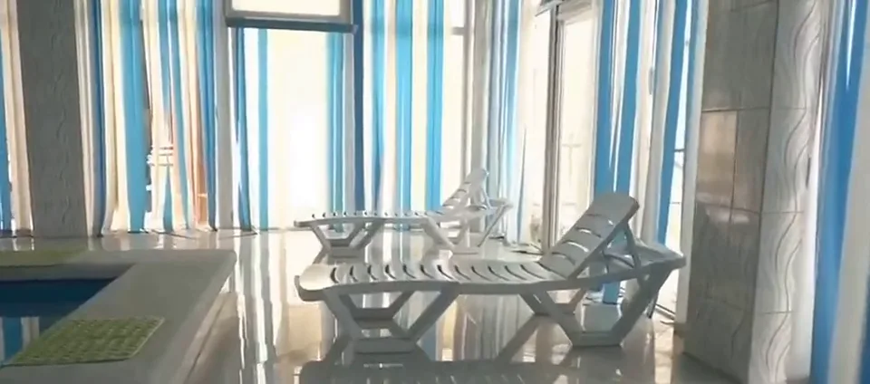 Бассейн с шезлонгами у панорамных окон