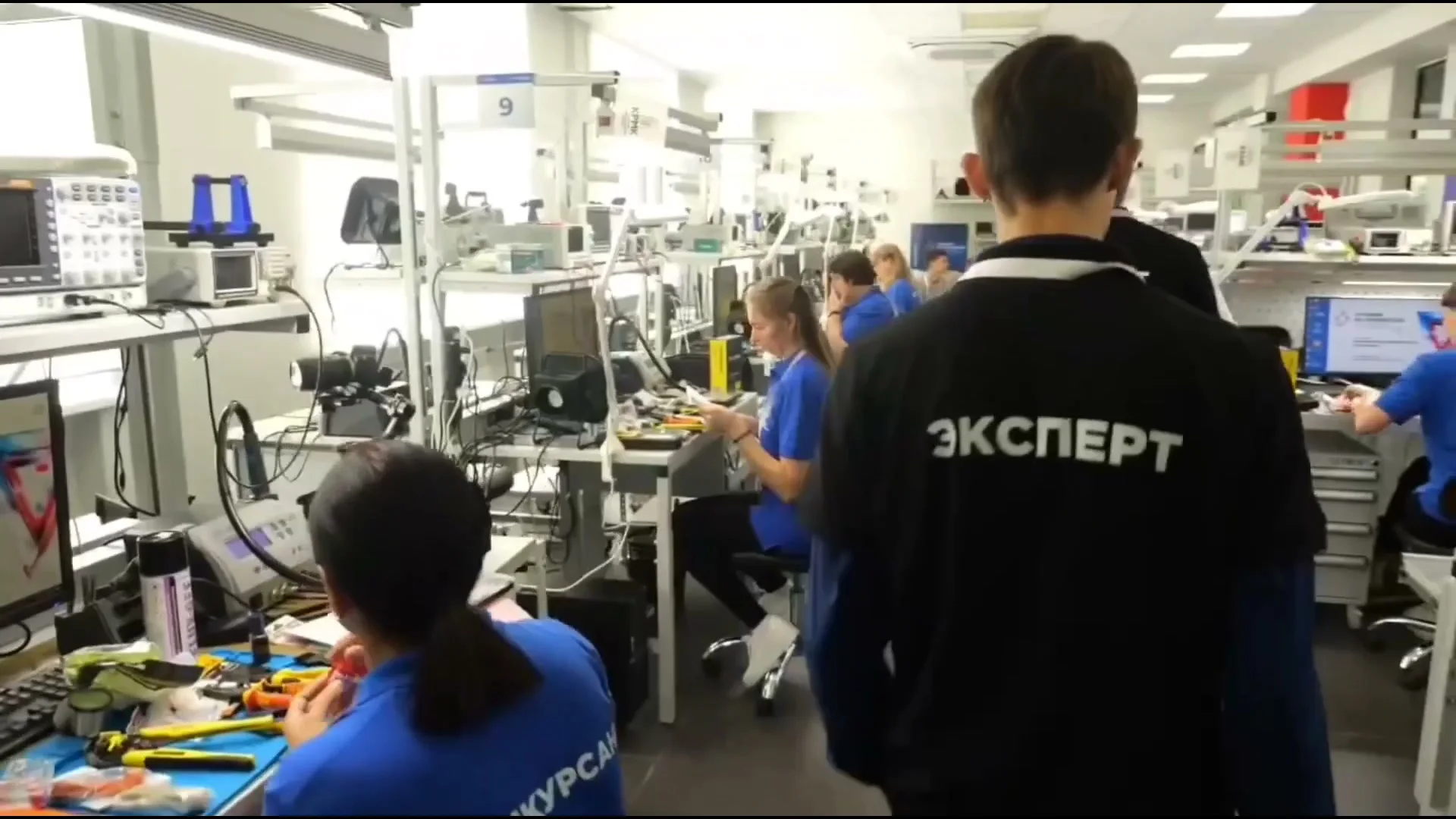 Мастерская: участники в куртках «Эксперт» и «Конкурсант» у рабочих мест с приборами